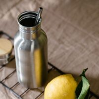 Nerūdijančio plieno gertuvė ir citrina ant stalo